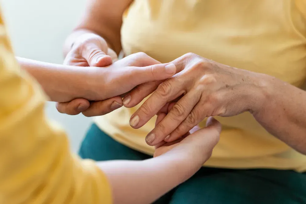 Caregiver gently holding an elderly person's hands
